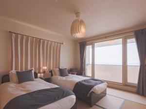 a bedroom with two beds and a large window at TOYA Station Villa in Lake Toya