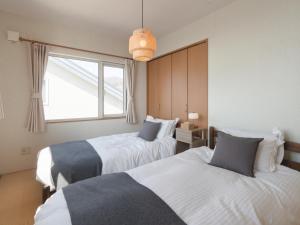 a hotel room with two beds and a window at TOYA Station Villa in Lake Toya