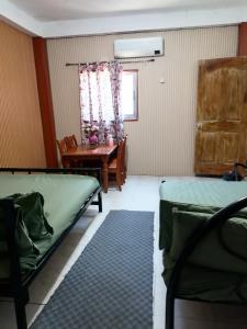 a room with two beds and a table and a window at Maraño's Home in Legazpi