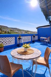 a patio with a table and chairs on a blue floor at La Joya Hostel Chafchaouen Cozy Stay with Terrace in Chefchaouen
