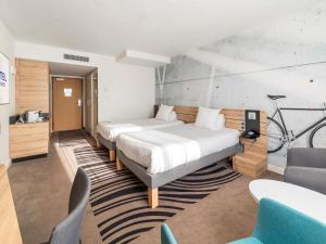 a hotel room with two beds and a bike on the wall at Novotel Kraków City West in Krakow