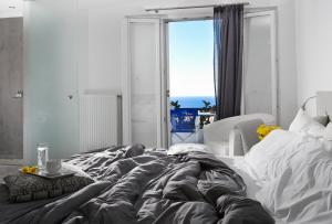 a bedroom with a large bed with a view of the ocean at Milos Villas Hotel in Fira