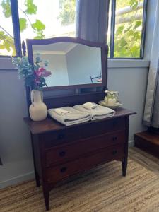 a wooden dresser with a mirror on top of it at Mulla Villa Farm cottage 1 in Wollombi
