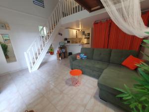 a living room with a green couch and a staircase at Duplex cosy avec piscine à 2mn de la plage - Kaz Ti Plaj in Les Trois-Îlets