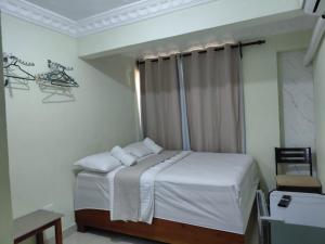 a bedroom with a bed with white sheets and a window at BNB Habitaciones Economicas - Cerca Aeropuerto Las Americas in La Viva