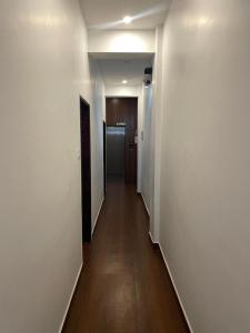 a hallway with white walls and wooden floors and a door at Niki Inn in Pondicherry