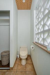 a bathroom with a toilet and a window at Tipani Villa Sovereign Palms CI in Rarotonga +12 photos