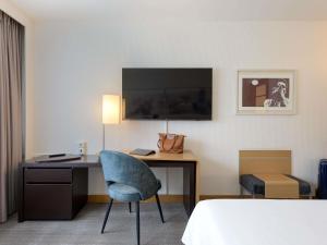 a hotel room with a desk and a chair at Novotel Aachen City in Aachen