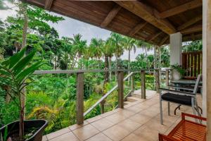 a porch with a bench and palm trees at Tipani Villa Sovereign Palms CI in Rarotonga