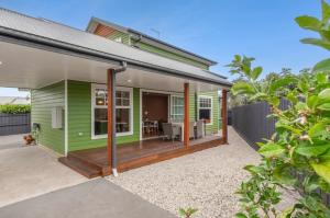 a green house with a porch with a patio at Peninsula Green Cottage for 14 guests in Capel Sound