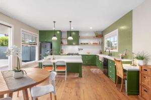 a kitchen with green cabinets and a table and chairs at Peninsula Green Cottage for 14 guests in Capel Sound