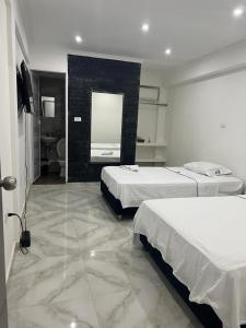 a hotel room with two beds and a mirror at Hotel Pacífico Azul in Bahía Solano +8 photos