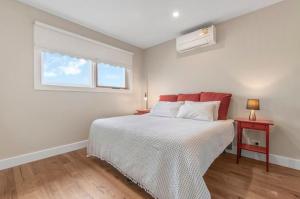 a white bedroom with a bed and a window at Peninsula Green Cottage for 14 guests in Capel Sound