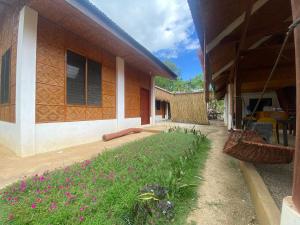 a building with a garden with pink flowers in front of it at Be My Guest Hostel in Panglao Island +21 photos