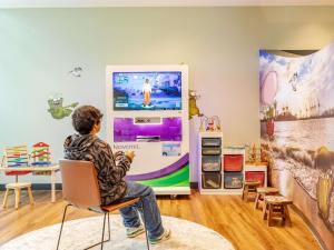 a person sitting in a chair in front of a tv at Novotel Hamburg City Alster in Hamburg