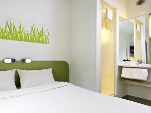 a bedroom with a white bed and a bathroom at ibis budget Hotel Brussels Airport in Diegem