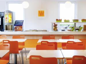 a fast food restaurant with tables and chairs at ibis budget Hotel Brussels Airport in Diegem