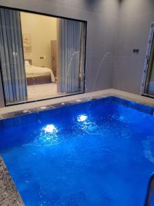 a large blue swimming pool in a room with a mirror at شاليه اغصان الباحة in Al Baha