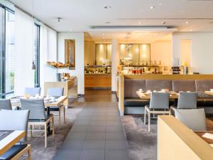 a restaurant with tables and chairs and a kitchen at Sunday Hotel Düsseldorf City Nord in Düsseldorf