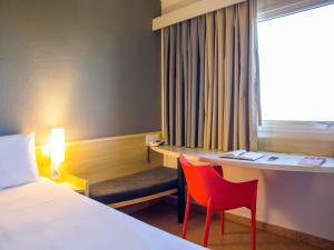 a hotel room with a bed and a desk and chairs at ibis Araçatuba in Araçatuba