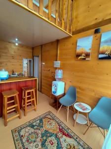 a room with wooden walls and a kitchen with chairs at Glamping Dieng New in Diyeng
