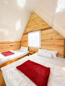 two beds in a room with wooden walls at Glamping Dieng New in Diyeng