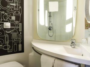 a bathroom with a sink and a mirror at Ibis Aéroport Bâle Mulhouse in Saint-Louis
