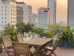 a wooden table and chairs on a balcony with a city skyline at MiAn Hotel Danang - Infinity Pool in Danang