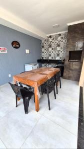 a dining room with a wooden table and a piano at Casa piscina privativa e Área Gourmet - Condomínio 24 hs in Araruama