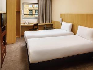 a hotel room with two beds and a desk at ibis Nottingham Centre in Nottingham +84 photos