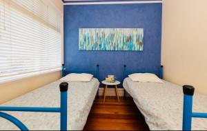 two twin beds in a room with blue walls at ABC Beachside Retreat in Rosebud