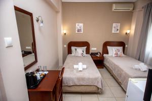 ein Zimmer mit zwei Betten, einem Schreibtisch und einem Spiegel in der Unterkunft Hotel Strimoniko in Asprovalta