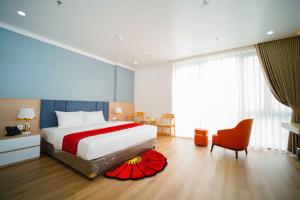 a bedroom with a large bed and a red chair at Eden Luxury Hotel in Thái Bình