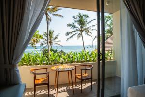 a balcony with a table and chairs and the ocean at Petti Petti Beach Club- Mirissa in Mirissa