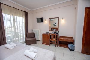 ein Hotelzimmer mit zwei Betten, einem Schreibtisch und einem Spiegel in der Unterkunft Hotel Strimoniko in Asprovalta