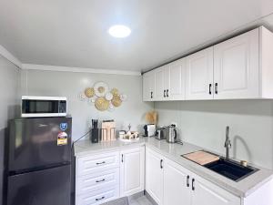 a kitchen with white cabinets and a black refrigerator at Alpaca Haven Farm in Rotorua
