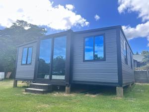 a gray tiny house sitting on top of a field at Alpaca Haven Farm in Rotorua