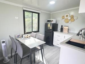 a kitchen with a white table and a black refrigerator at Alpaca Haven Farm in Rotorua +8 photos