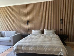 a bedroom with a large bed and a chair at Gala 1 - The Old Coolstore in Merricks North +1 photo