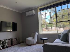 a living room with a couch and a chair and a tv at Gala 1 - The Old Coolstore in Merricks North