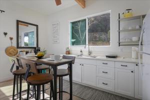 a kitchen with white cabinets and a table with stools at Quiet 2BR Kona Retreat Beach Gear BBQ Patio in Kailua-Kona