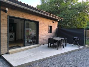 a patio with a table and chairs and a grill at Studio indépendant face à la forêt in Aureilhan