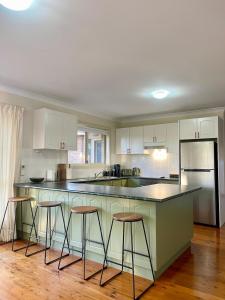 a kitchen with white cabinets and bar stools at Ficus Cottage - 3 Bed 2 Bath in Wentworth Falls +16 photos