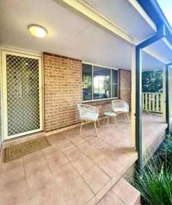 a patio with two chairs and a brick wall at Ficus Cottage - 3 Bed 2 Bath in Wentworth Falls