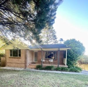 a small brick house with a porch and a chair at Ficus Cottage - 3 Bed 2 Bath in Wentworth Falls