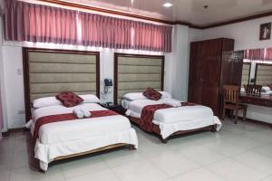 a bedroom with two beds and a desk in it at HOTELINDA Suites in Vigan +12 photos