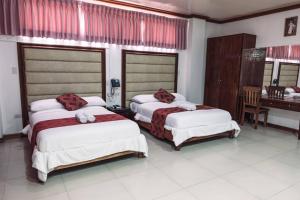 a bedroom with two beds and a desk in it at HOTELINDA Suites in Vigan