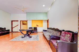 a living room with a couch and a table at Super Hotel O CSIR Pappanamcode Formerly Ambadi Guest House in Poojapura