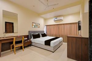 a bedroom with a bed and a desk and a television at Townhouse Vadodara Railway Station Road Formerly Hotel Raajpath in Vadodara +40 photos