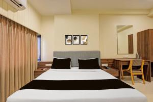 a bedroom with a large bed and a desk at Townhouse Vadodara Railway Station Road Formerly Hotel Raajpath in Vadodara